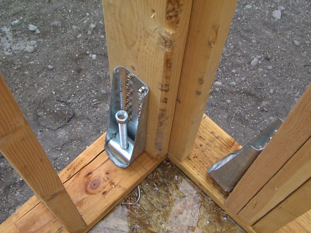 Hold-down anchor bolted to a wood stud and foundation representing the seismic framing hardware required for higher demand custom homes