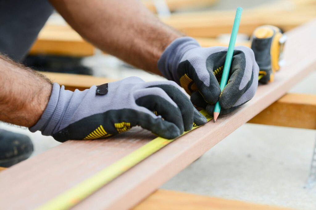 Framer marking a precise measurement on construction lumber representing the accuracy that prevents costly finishing headaches