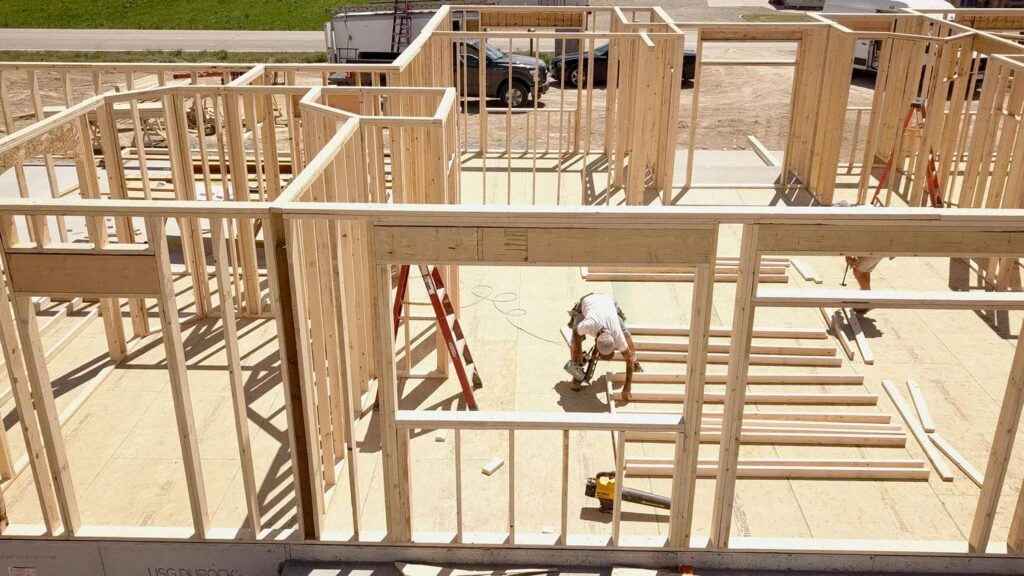 Organized framing jobsite with a carpenter reviewing drawings, reflecting how Madera approaches luxury framing