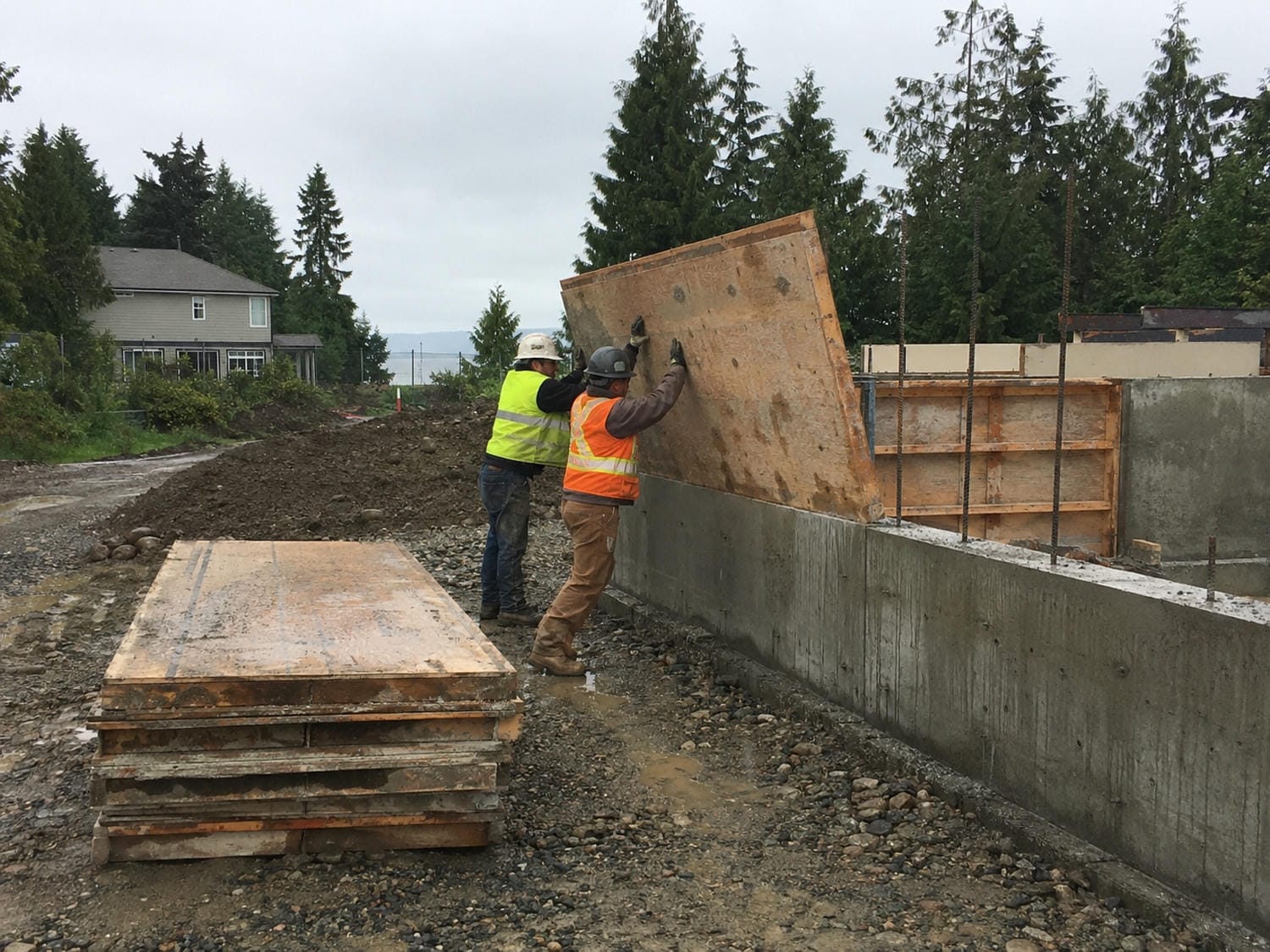 Carpentry crew removing concrete forms from a new residential foundation on a wet Metro Vancouver site