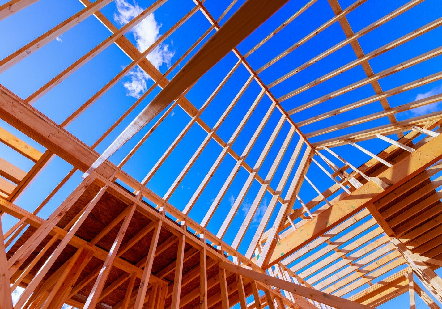 exposed wood roof framing structure against blue sky