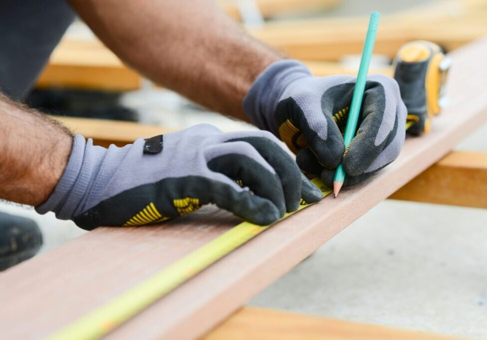 Framer marking a precise measurement on construction lumber representing the accuracy that prevents costly finishing headaches