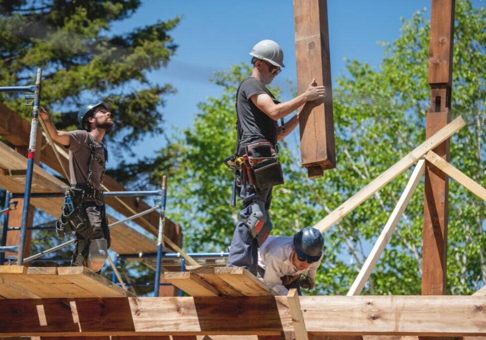 Framing crew setting a long engineered LVL beam over an open main floor in a Lower Mainland custom home.